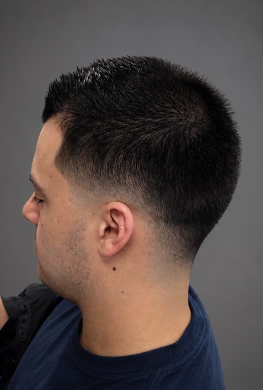 Thick dark hair kept full on top and faded down the back of the neck.