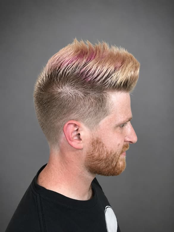 Blond hair spiked up with pink running through the top and the sides faded short.